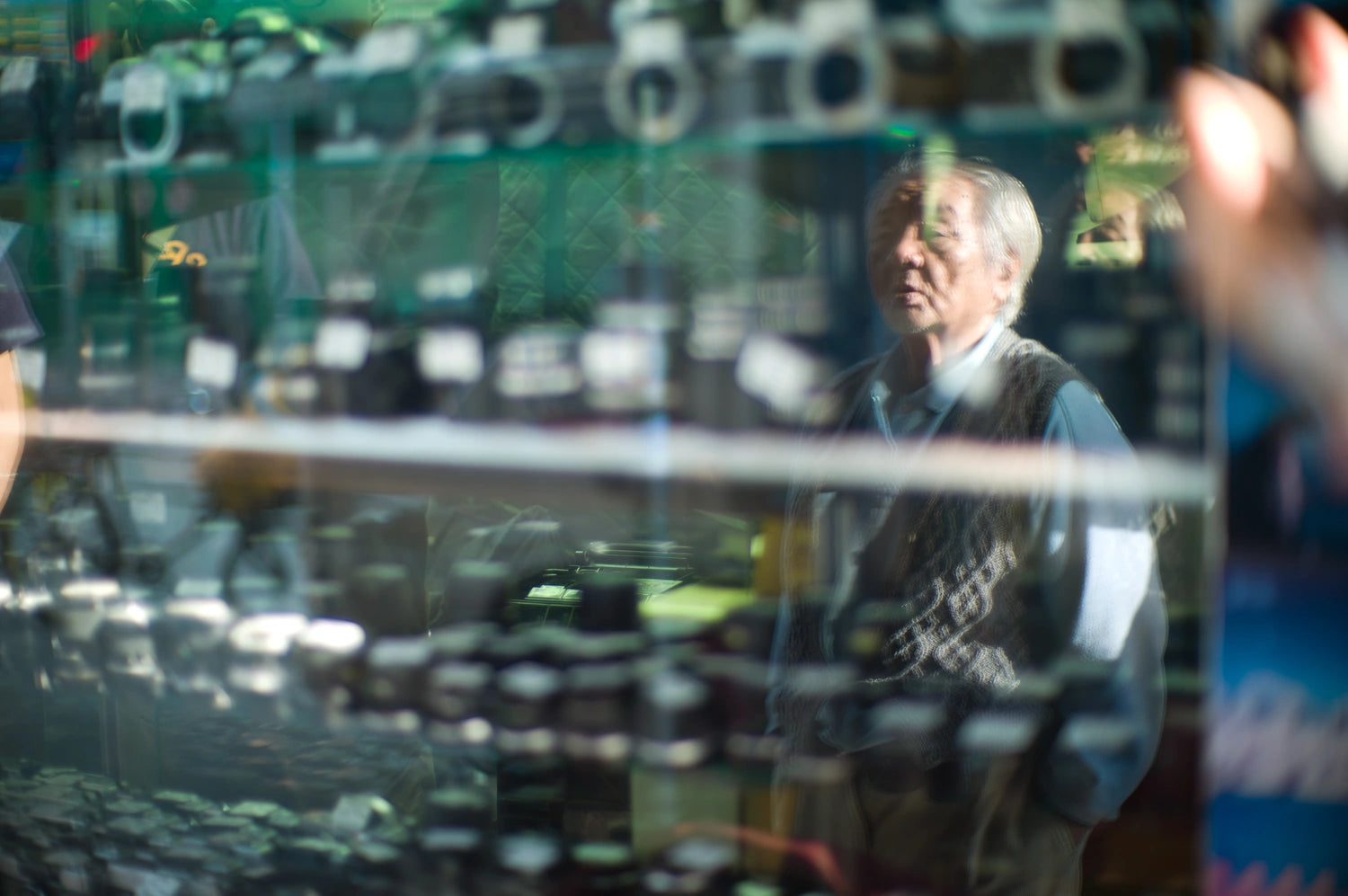 best-places-for-street-photography-in-hong-kong-sham-shui-po-elderly-man-reflected-glass-camera-shop