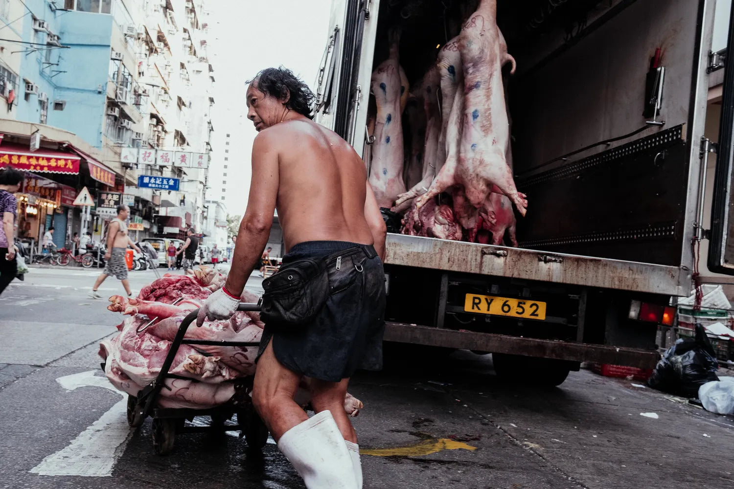 best-places-for-street-photography-in-hong-kong-sham-shui-po-shirtless-worker-unloading-meat-carcasses-truck
