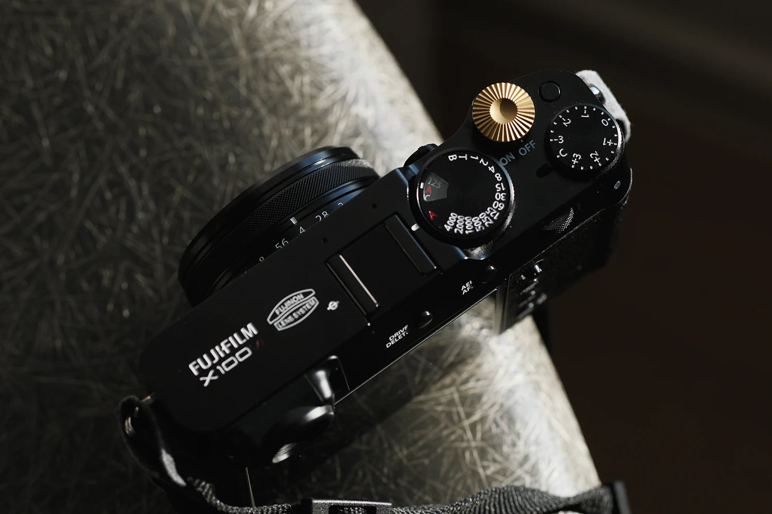 Black Fujifilm camera on a textured surface with a dark background air clicker brass