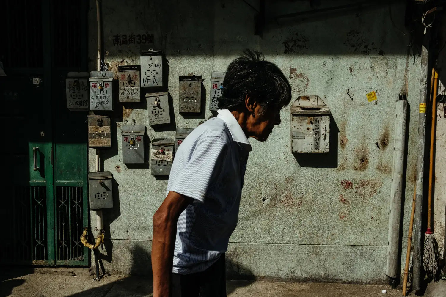 best-places-for-street-photography-in-hong-kong-sham-shui-po-elderly-man-walking-mailboxes-wall-dramatic-shadow